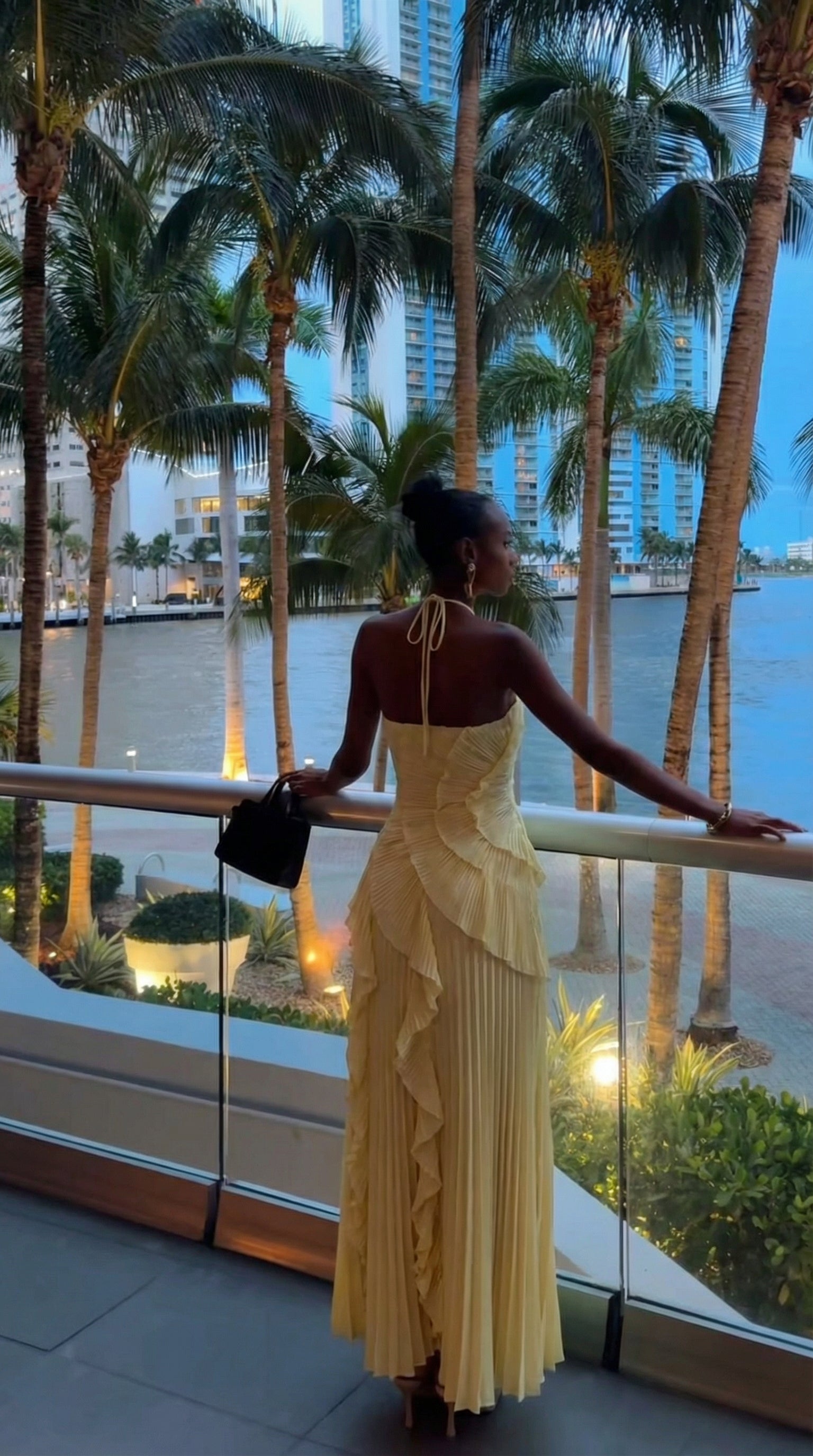 Yellow halter maxi dress worn on a balcony, back view