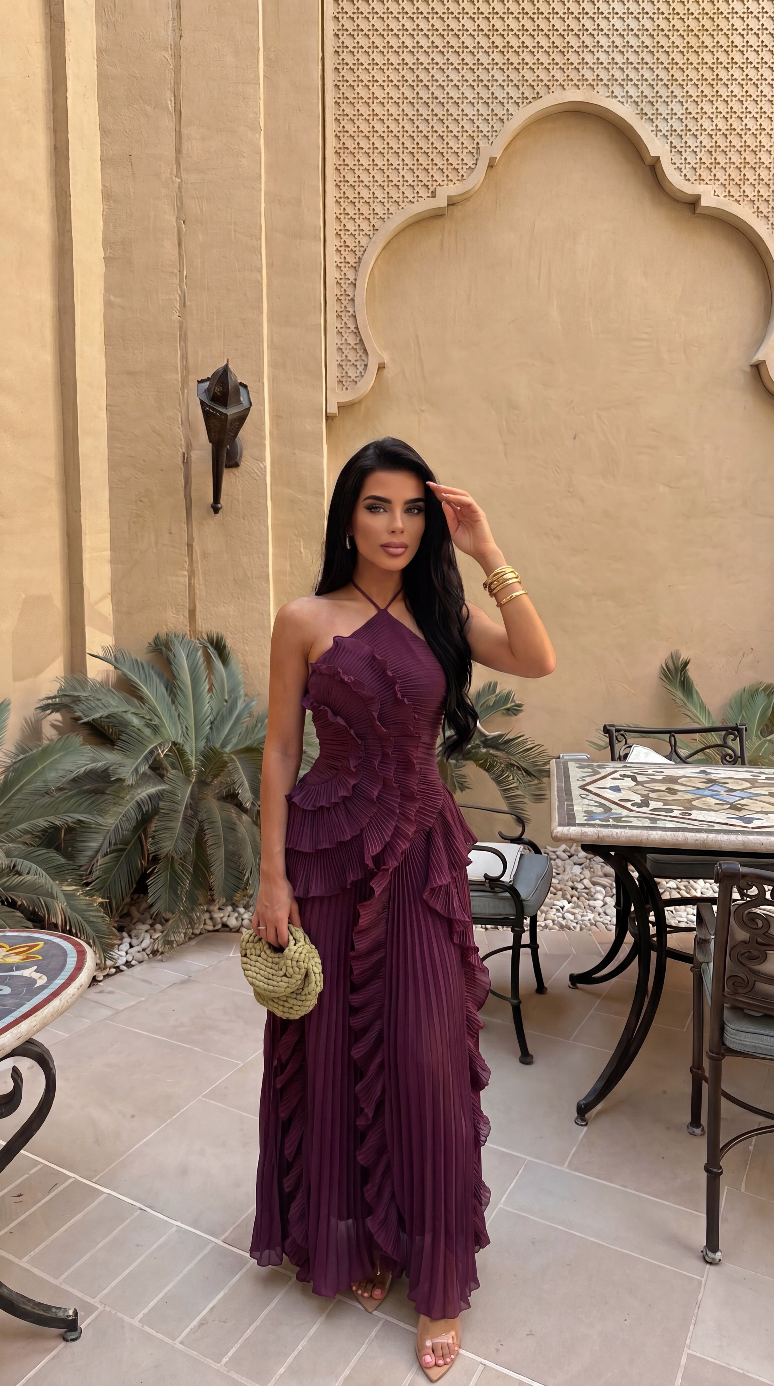 Plum halter maxi dress worn in a courtyard, front view
