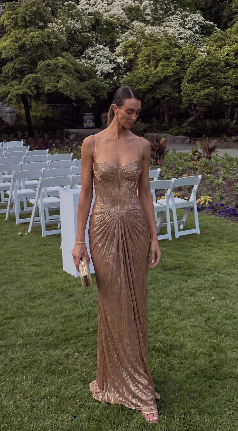 Gold corset maxi dress styled to highlight the flowing pleated skirt.