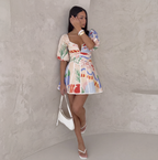 Multicolour print mini dress with puff sleeves, worn against a wall