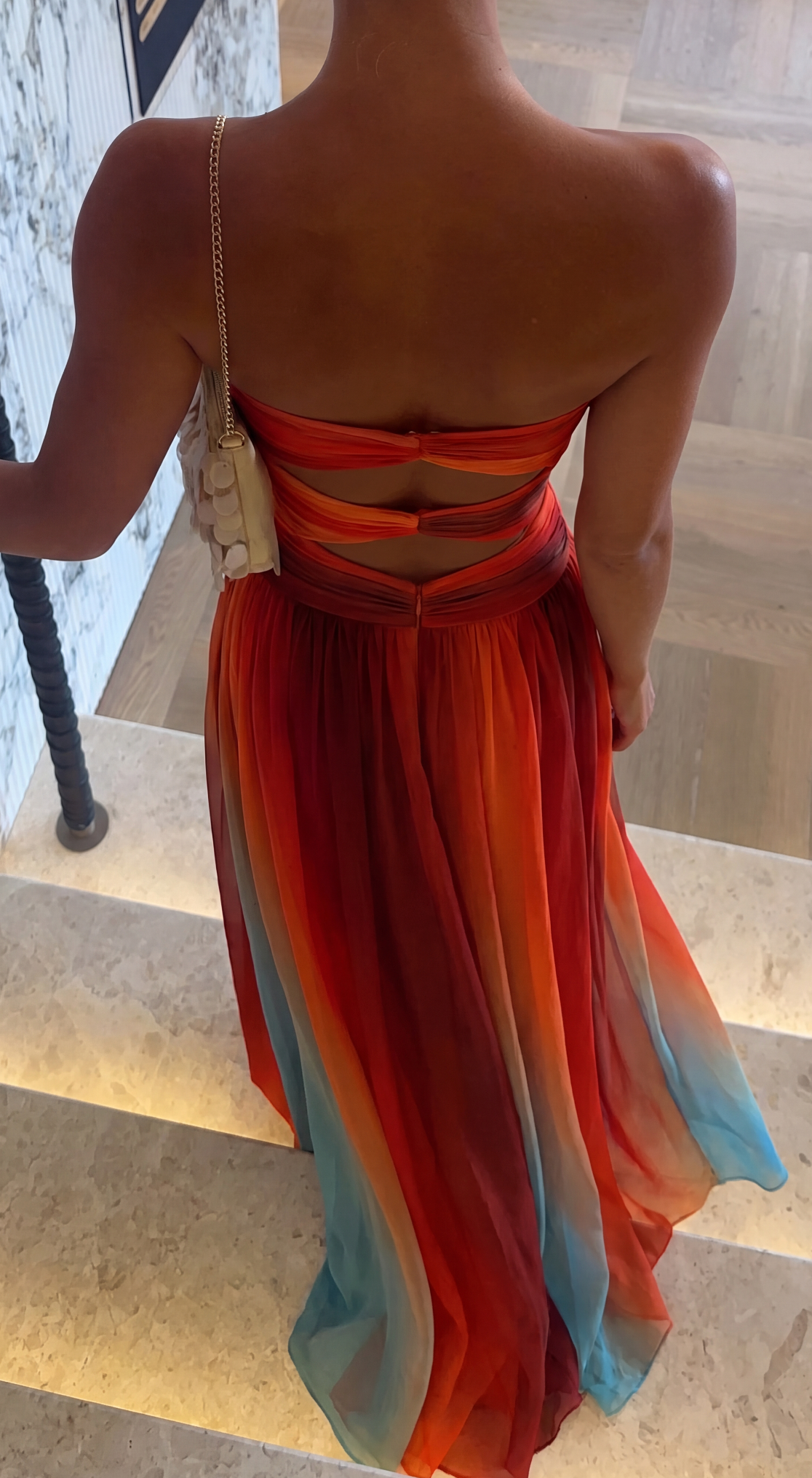 Back view of multicolour ombre strapless maxi dress on a staircase