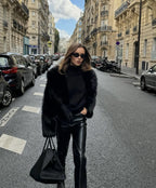 Black faux fur coat worn over knitwear, styled look