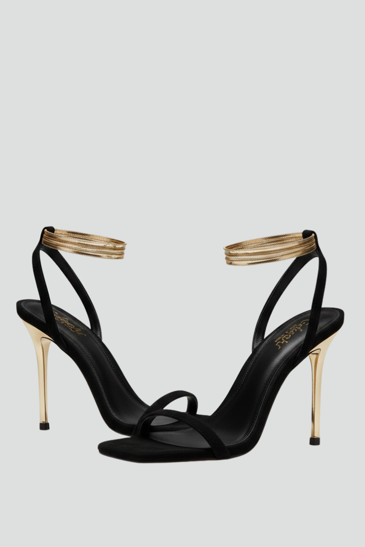 Black heeled sandals with a gold wrap ankle strap, studio pair shot