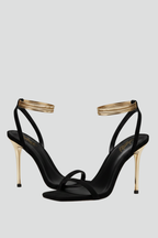 Black heeled sandals with a gold wrap ankle strap, studio pair shot