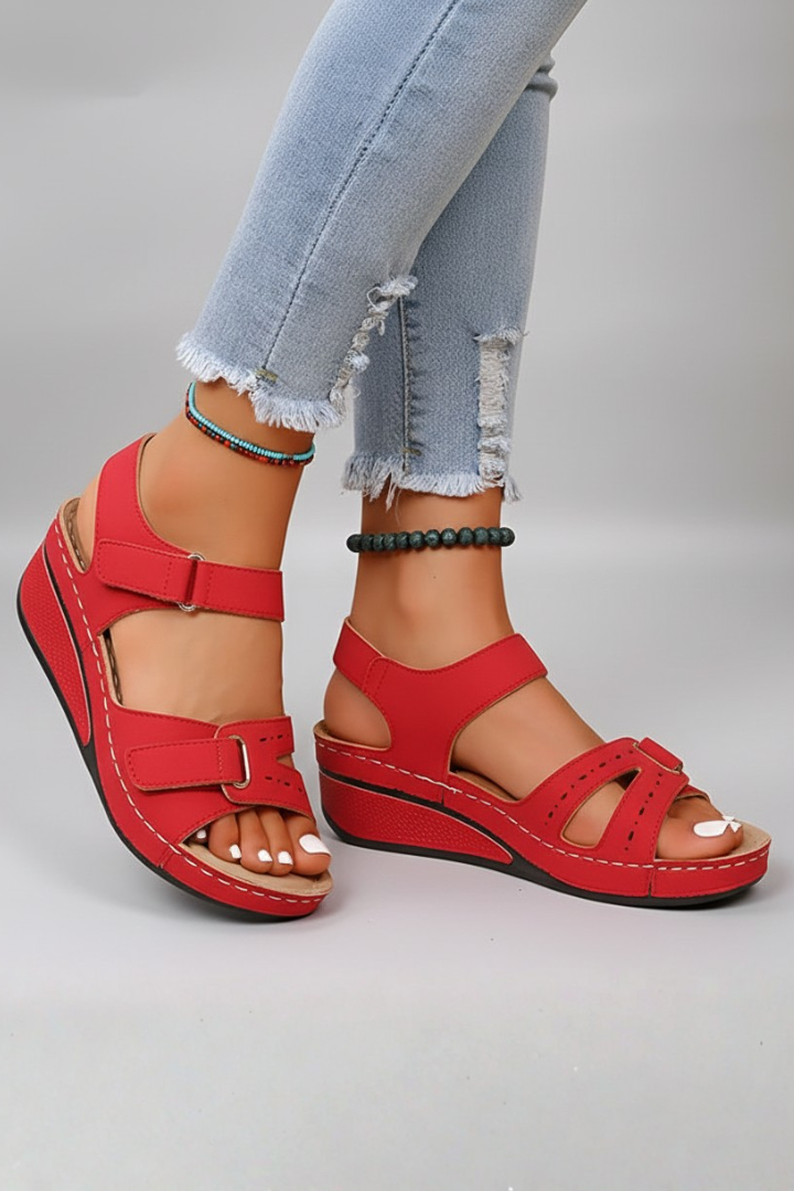Red wedge sandals with hook-and-loop straps worn with denim