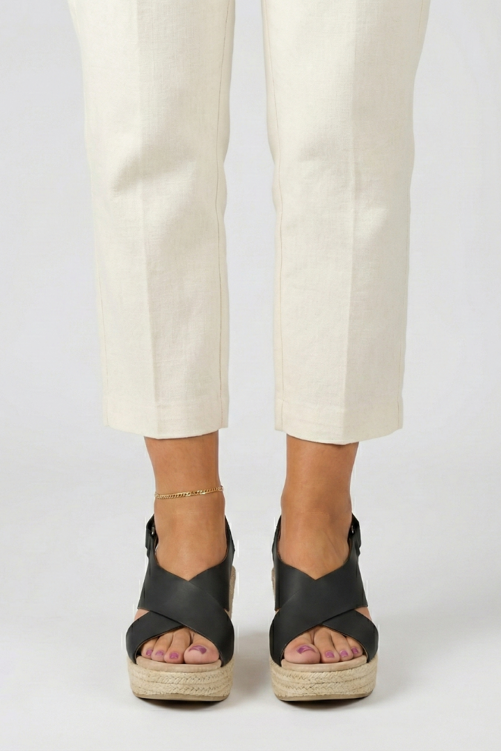 Black espadrille wedge sandals worn with cream trousers, front view