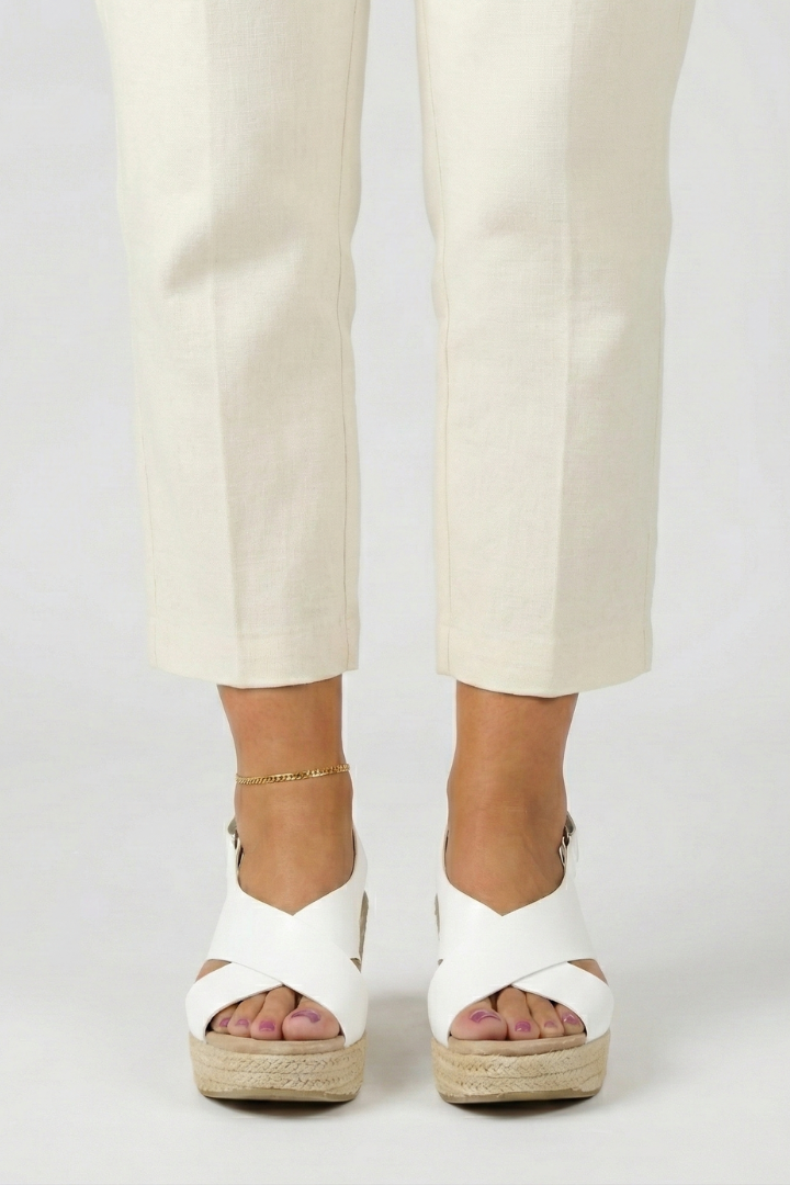 White espadrille wedge sandals with crossover straps, worn with cream trousers