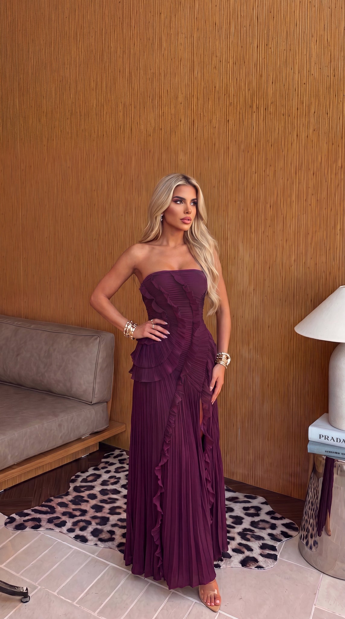 Plum strapless maxi dress shown with its asymmetrical pleated skirt.