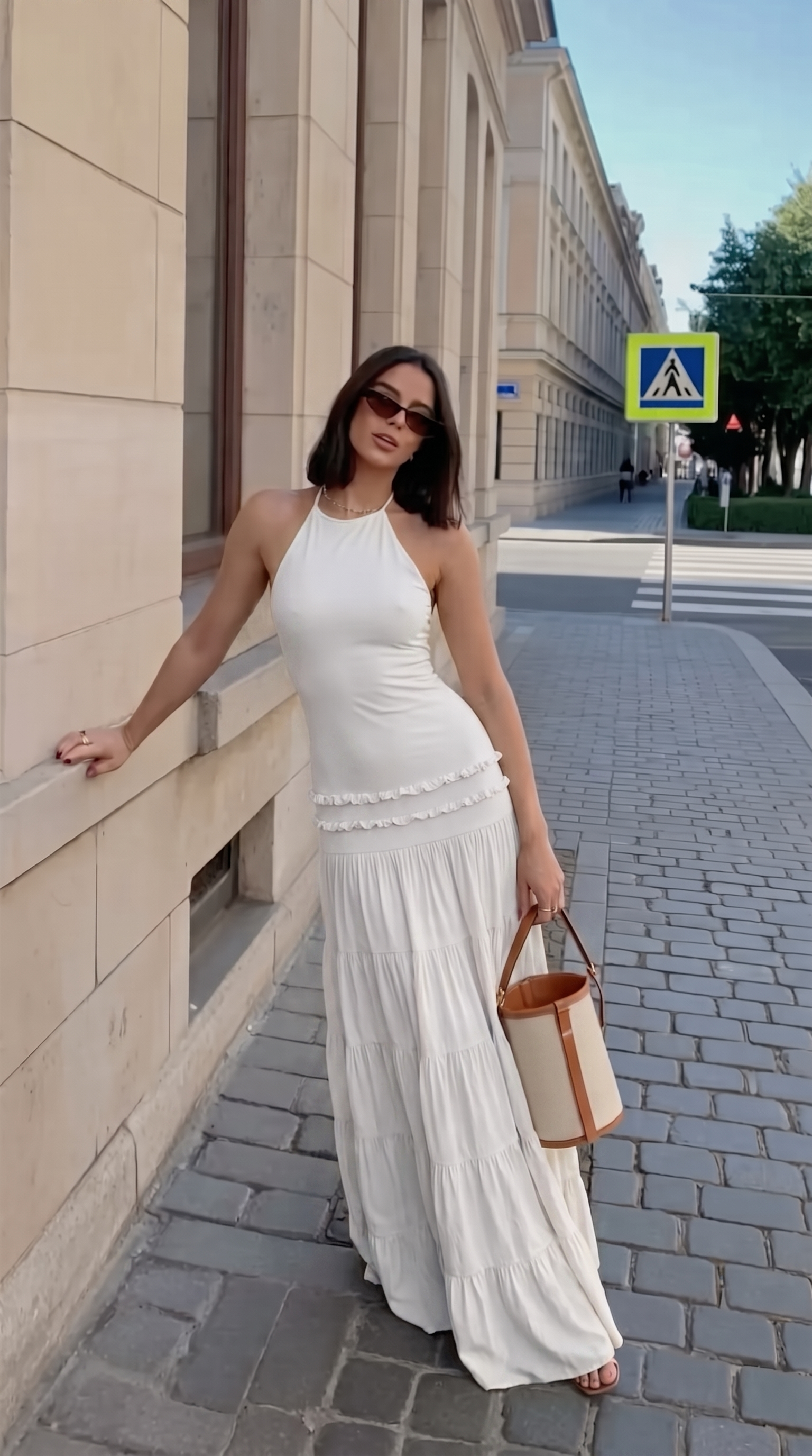 White halter maxi dress with tiered skirt worn on a city street