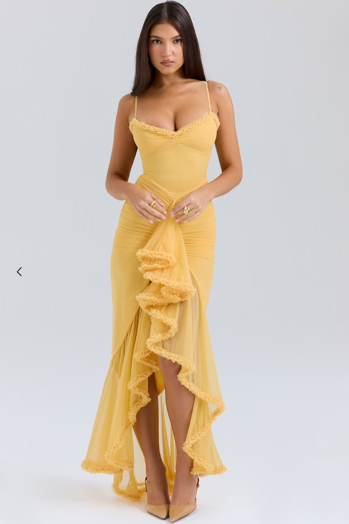 Yellow bodycon maxi dress shown with its ruffled high slit.