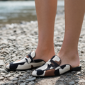 Brown cow print slip-on loafers worn outdoors, close-up view