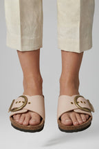 Cream buckle comfort sandals worn with tailored trousers, front view