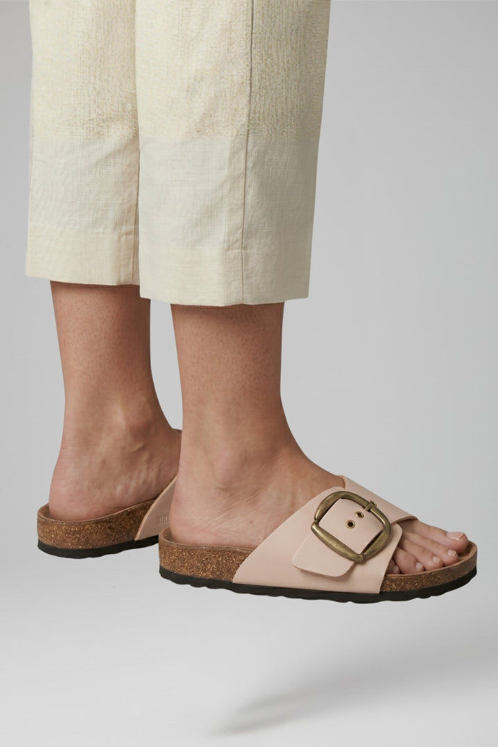 Close-up of cream buckle comfort sandals with tailored trousers
