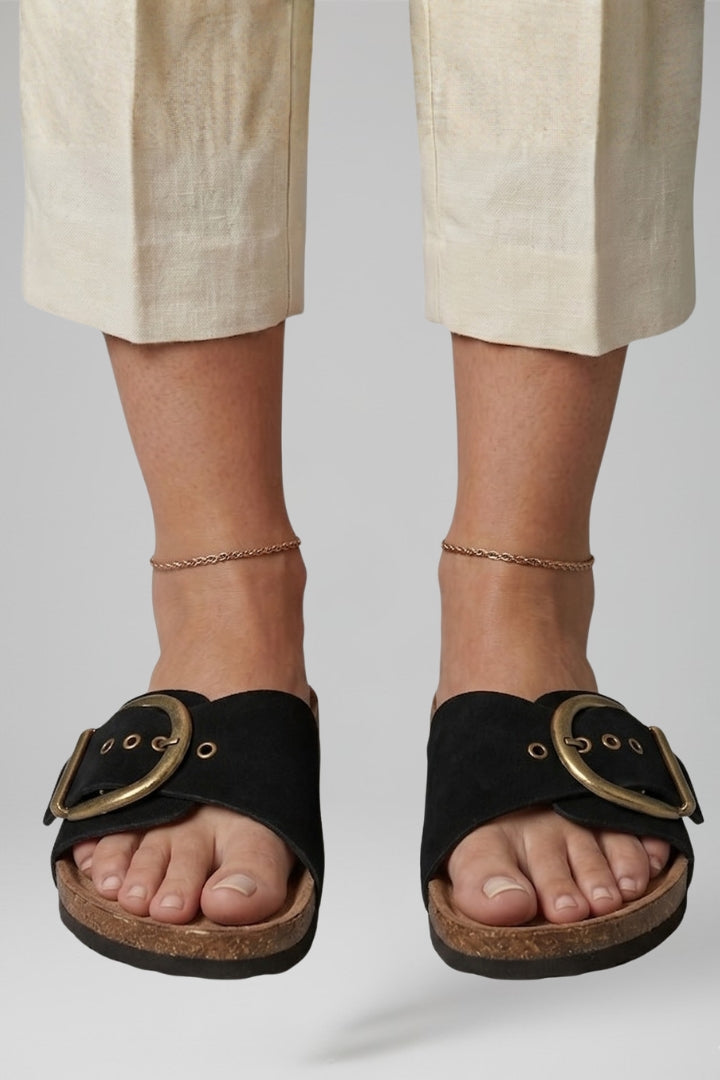 Black buckle comfort sandals worn with linen trousers, front view